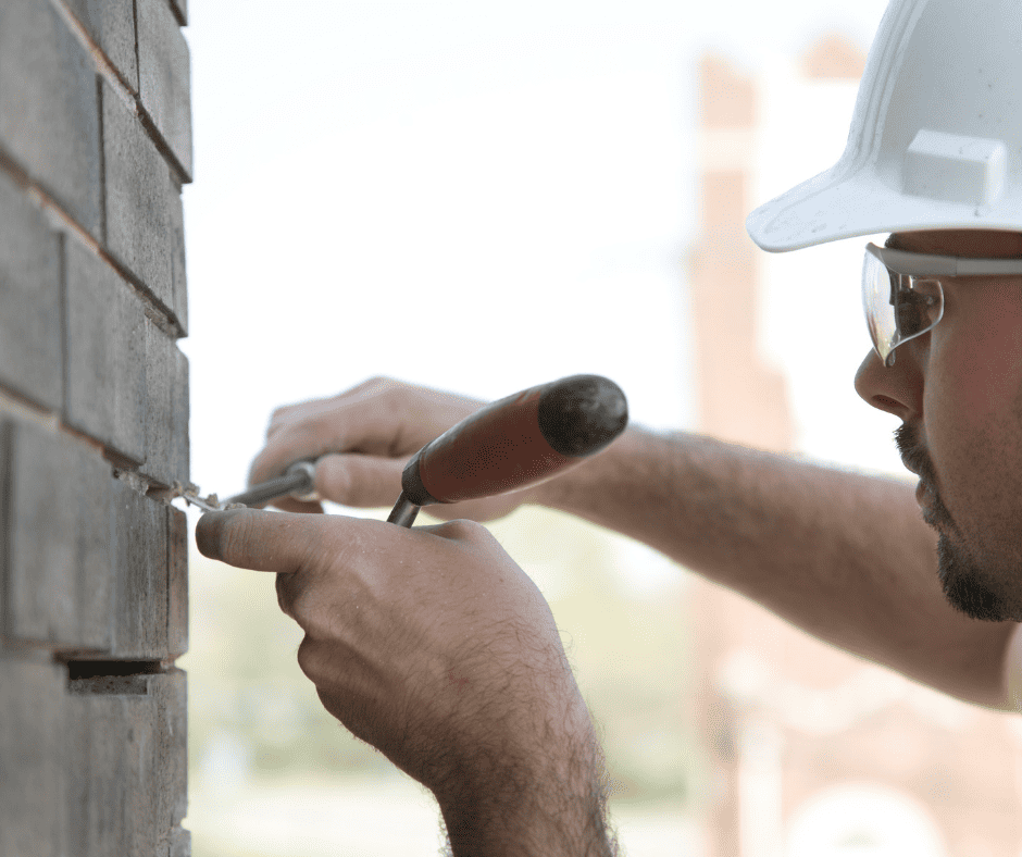 A man repointing brick wall