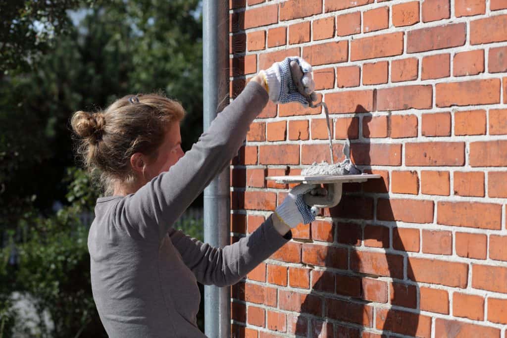 Young woman sealing her brick masonry