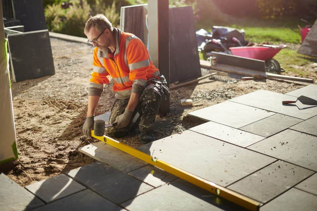 Male worker laying a slate during patio installation
