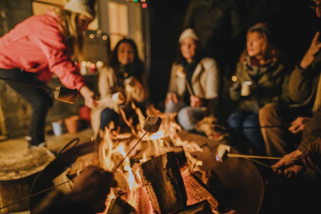 Group of friends toasting marshmallows on a fire pit